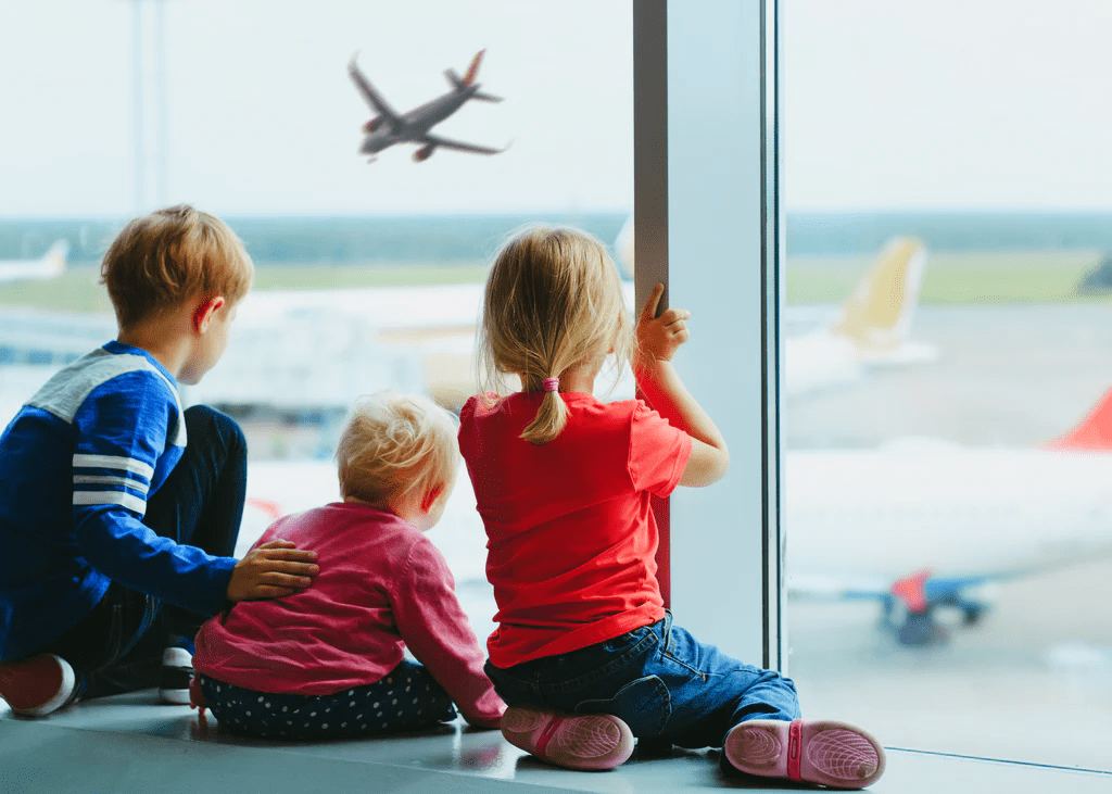 Children watching planes at the airport window.